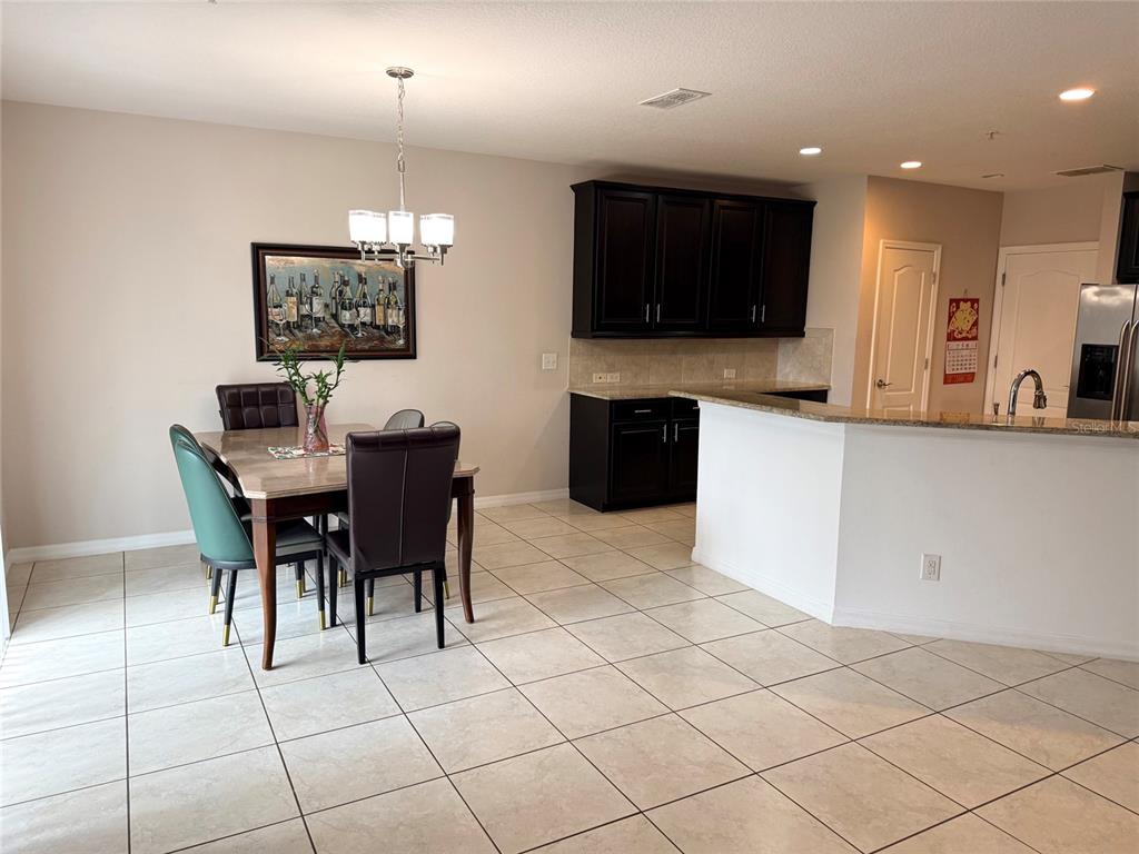 A dining area with a table and chairs sits adjacent to a kitchen with dark cabinets — 2084 WATER TUPELO WAY, OCOEE, FL