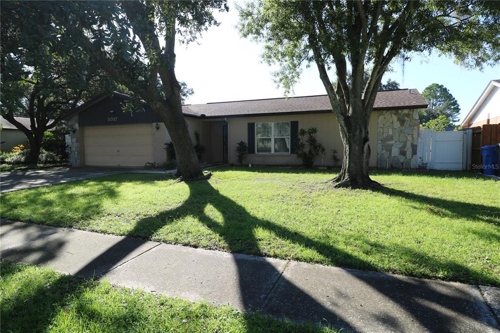 A single-story house with a tan exterior, stone accents, and a two-car garage — 5017 OAKSHIRE DR, TAMPA, FL