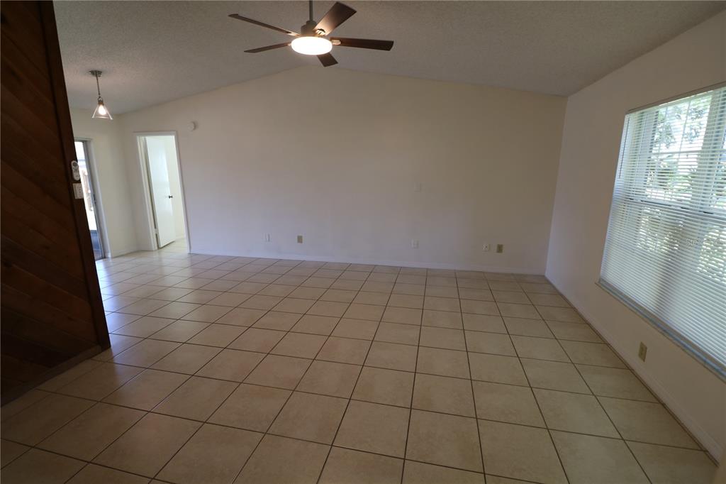 A spacious room with beige tile flooring, a ceiling fan, and a large window — 5017 OAKSHIRE DR, TAMPA, FL