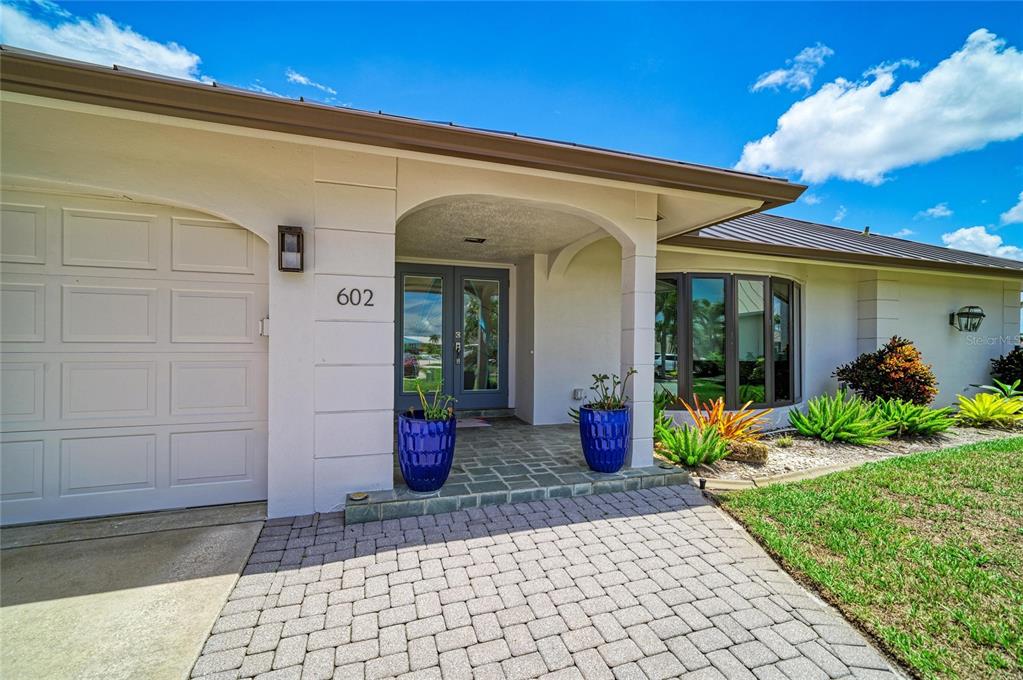 The exterior of a house features a paved driveway, a garage, and a covered entryway — 602 VIA TUNIS, PUNTA GORDA, FL