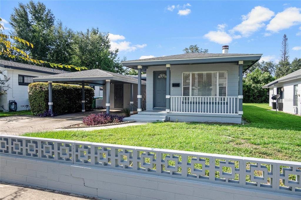 A gray single-story house with a front porch and carport behind a decorative concrete wall — 450 W CANTON AVENUE, WINTER PARK, FL