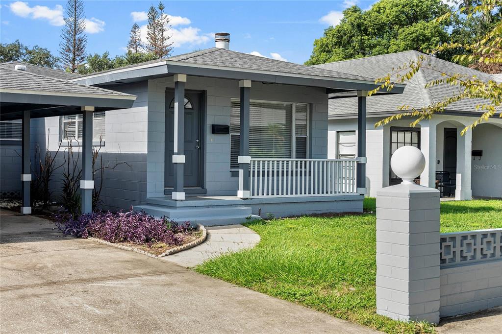 A gray concrete block house features a covered front porch with white railings and columns — 450 W CANTON AVENUE, WINTER PARK, FL