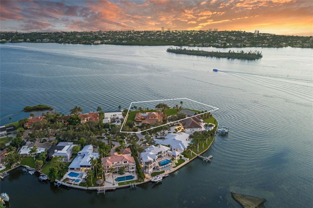 An aerial view shows a waterfront estate on a peninsula with a highlighted property boundary — 1136 N LAKE SHORE DRIVE, SARASOTA, FL