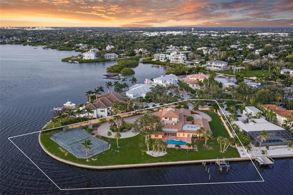 An aerial view of a waterfront estate featuring a tennis court, pool, and large lawn — 1136 N LAKE SHORE DRIVE, SARASOTA, FL