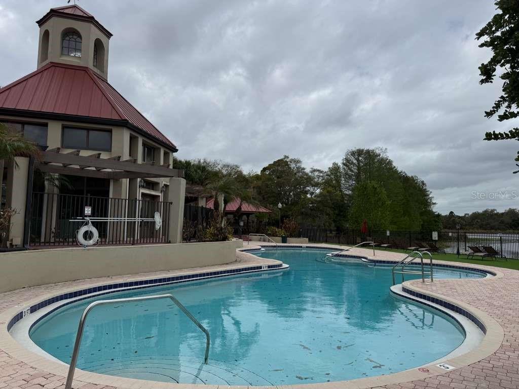 An outdoor swimming pool with a metal railing and a clubhouse building in the background — 216 AFTON SQUARE UNIT 304, ALTAMONTE SPRINGS, FL