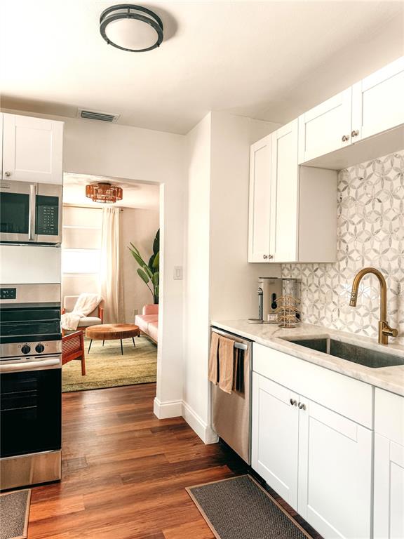 A kitchen with white cabinets, stainless steel appliances, and a patterned tile backsplash — 107 4TH AVENUE, ST PETE BEACH, FL