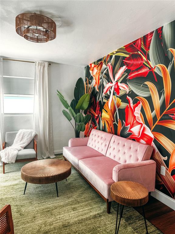 A living room features a pink velvet sofa, tropical wallpaper, and a round wooden coffee table — 107 4TH AVENUE, ST PETE BEACH, FL