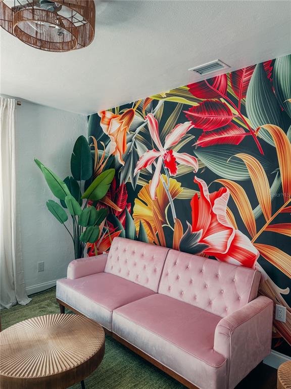 A living room features a pink velvet sofa against a vibrant tropical floral wallpaper — 107 4TH AVENUE, ST PETE BEACH, FL