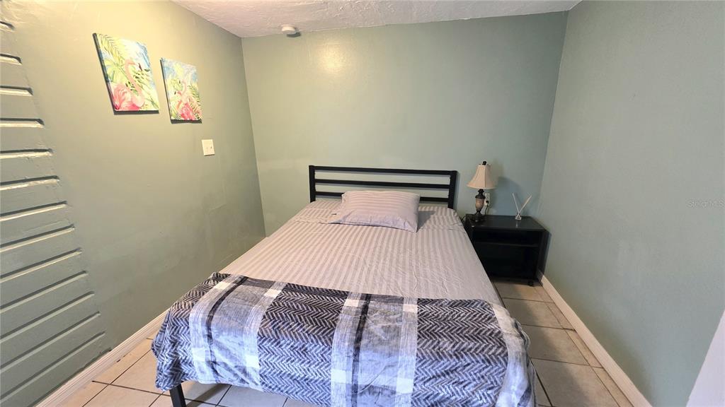 A bedroom features a bed with a plaid blanket, a nightstand, and two flamingo wall decorations — 2031 4TH STREET, SARASOTA, FL