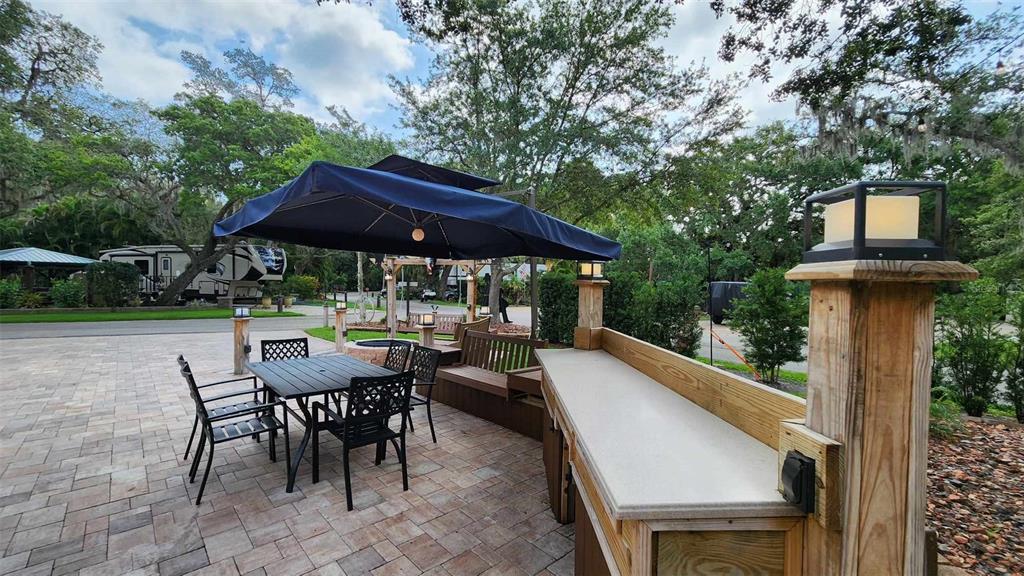 An outdoor patio features a dining set under a blue umbrella, a bar, and seating — 371 BOB CAT LANE, RIVER RANCH, FL
