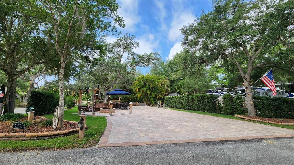 A paved driveway leads to an outdoor seating area with a pergola and fire pit — 371 BOB CAT LANE, RIVER RANCH, FL