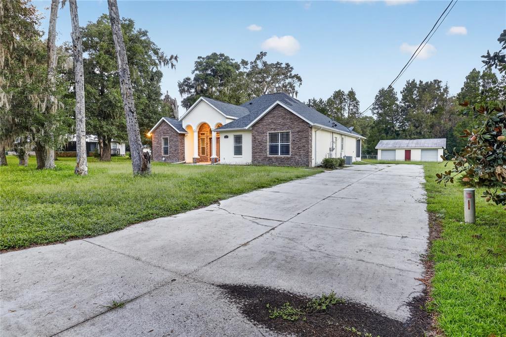 A single-story house with stone accents and a long concrete driveway sits on a lawn — 3049 W LAUREL STREET, LECANTO, FL