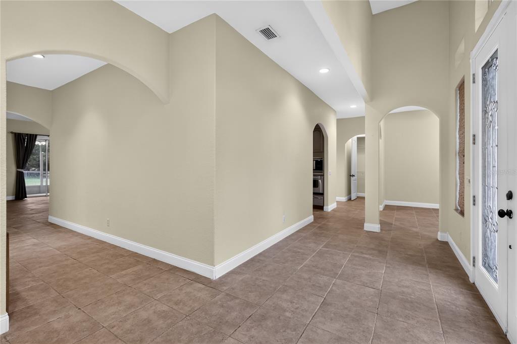 An entryway with beige walls, tile flooring, arched doorways, and a glass-paneled front door — 3049 W LAUREL STREET, LECANTO, FL