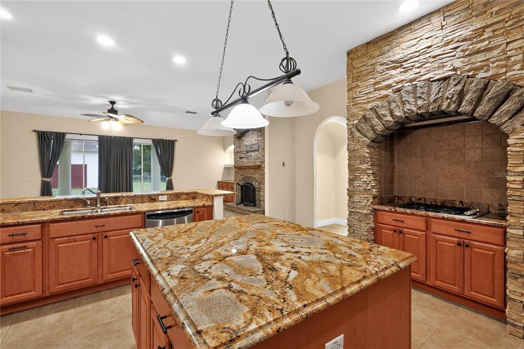 A kitchen features wood cabinets, granite countertops, a central island, and a stone-encased stove area — 3049 W LAUREL STREET, LECANTO, FL