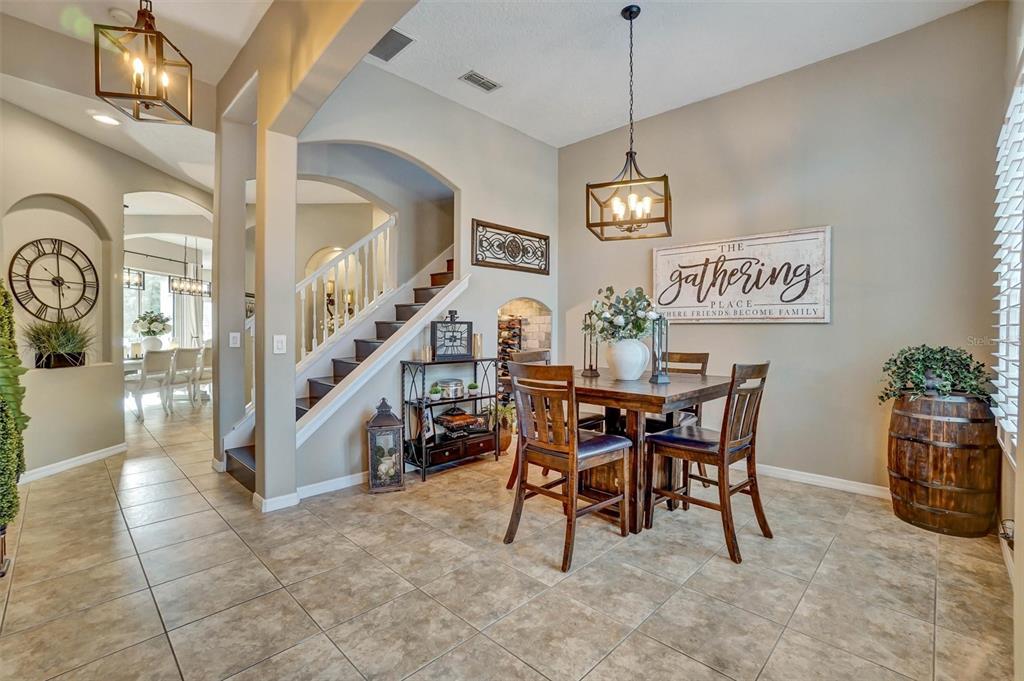 A dining area features a wooden table, chairs, a hanging light fixture, and a staircase — 324 TUDOR SPRING COURT, ORLANDO, FL