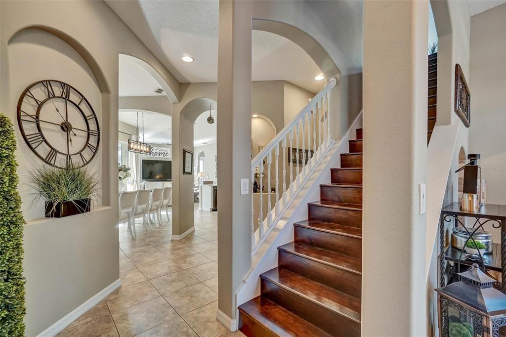 An entryway features a wooden staircase, arched architectural details, and a large wall clock — 324 TUDOR SPRING COURT, ORLANDO, FL