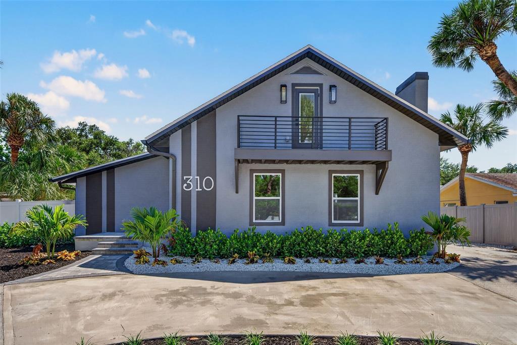 A two-story gray house with a balcony, a concrete driveway, and palm trees — 310 PARK STREET N, ST PETERSBURG, FL