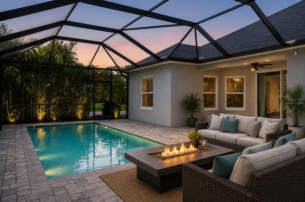 A screened-in patio features a swimming pool, a fire pit, and outdoor lounge furniture — 4727 CREEKRIDGE COURT, BRADENTON, FL
