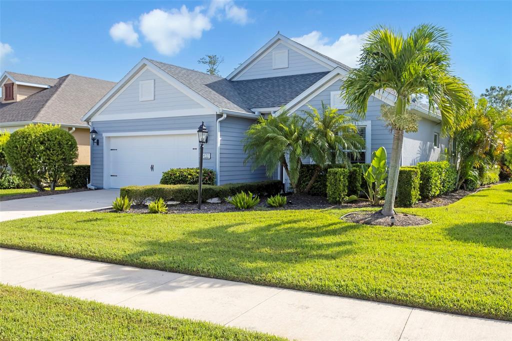 A single-story blue house with a two-car garage and palm trees in the front yard — 4727 CREEKRIDGE COURT, BRADENTON, FL