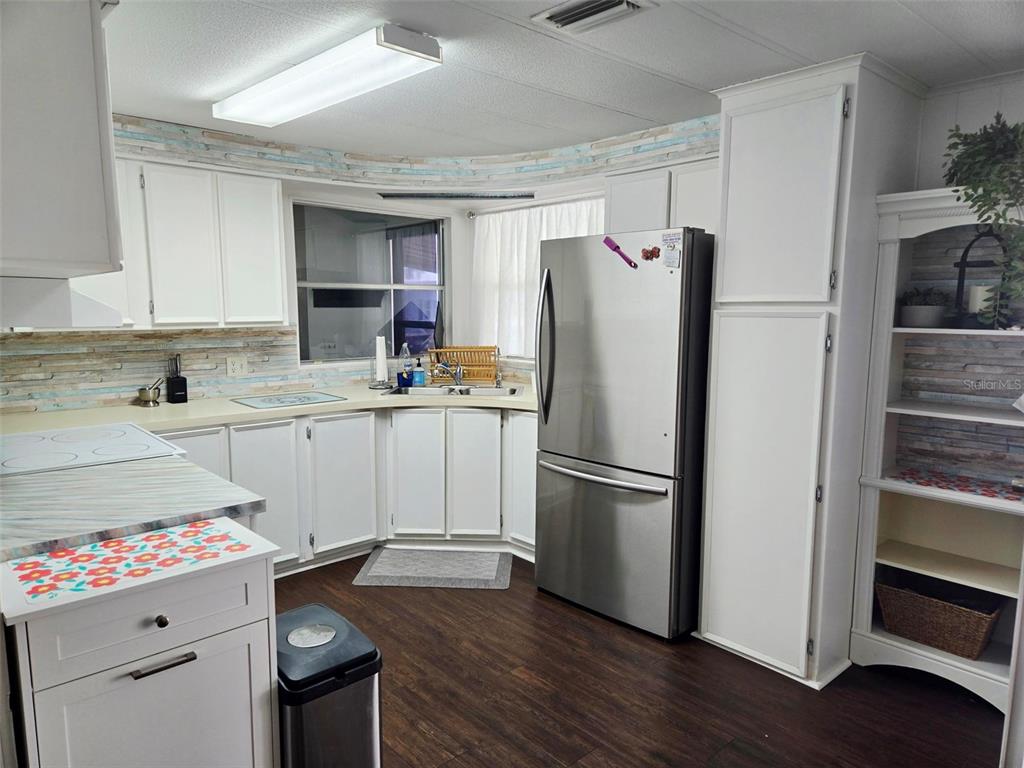A kitchen features white cabinets, stainless steel appliances, and a light-colored backsplash — 5316 53RD AVE E UNIT D14, BRADENTON, FL