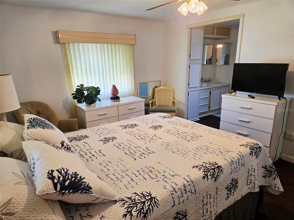 A bedroom features a bed with coral-patterned bedding, a white dresser, and an attached bathroom — 5316 53RD AVE E UNIT D14, BRADENTON, FL