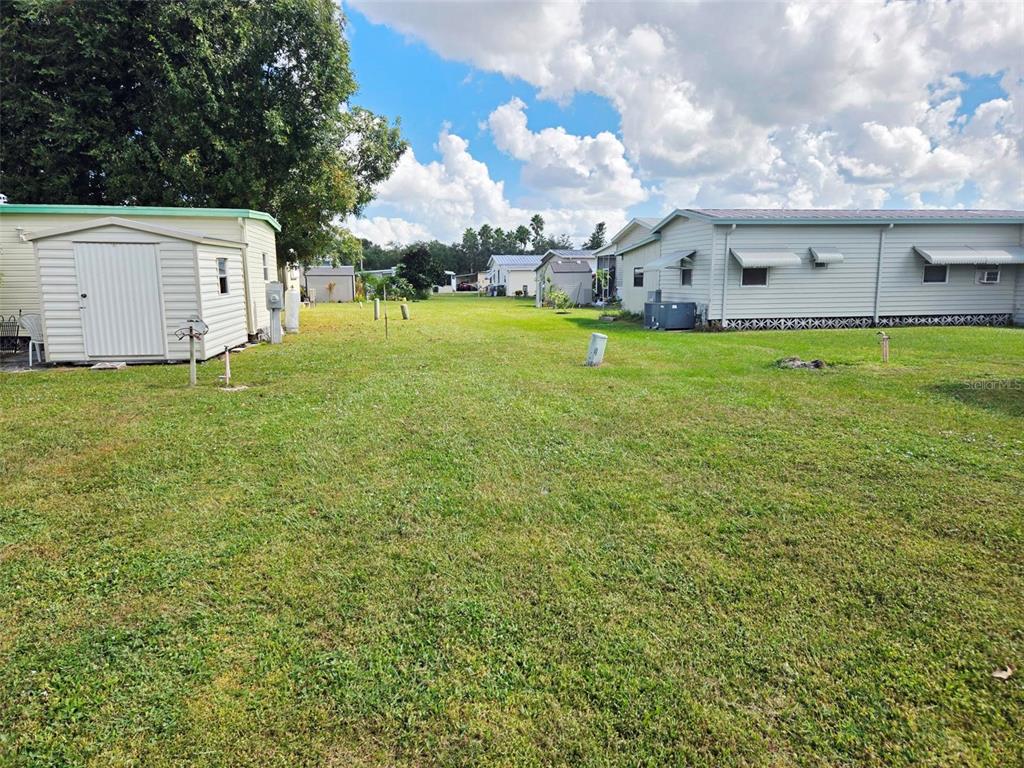 A grassy lot sits between two mobile homes with a small shed on the left — 5316 53RD AVE E UNIT D14, BRADENTON, FL