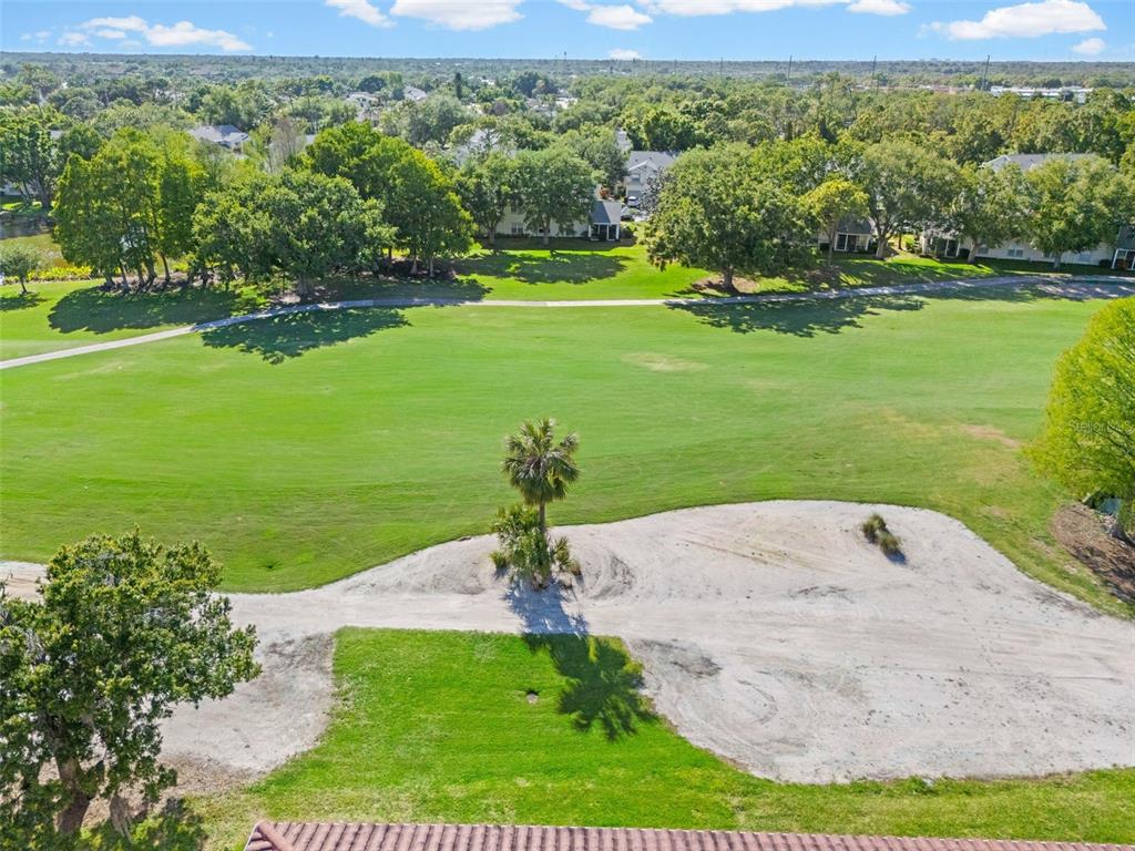 An aerial view shows a sandy golf course bunker and a palm tree on green grass — 6503 STONE RIVER ROAD UNIT 204, BRADENTON, FL