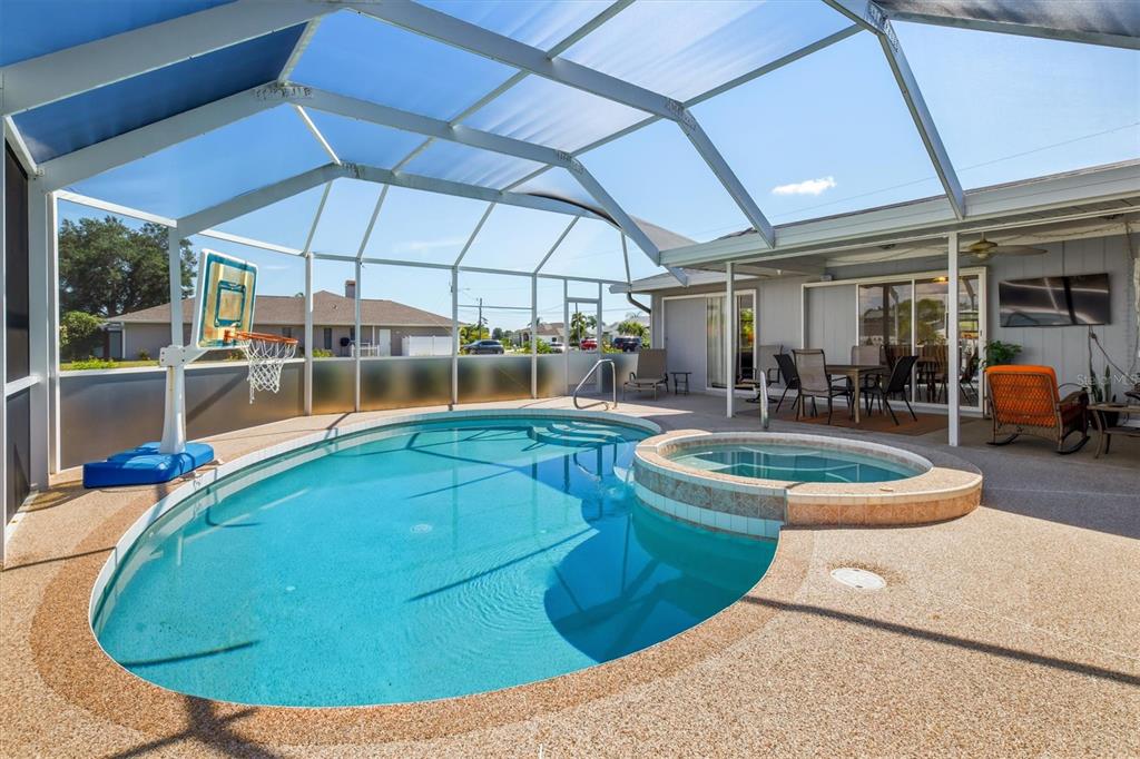 A screened-in pool area features a kidney-shaped pool, a raised spa, and a basketball hoop — 26392 LANCER LANE, PUNTA GORDA, FL