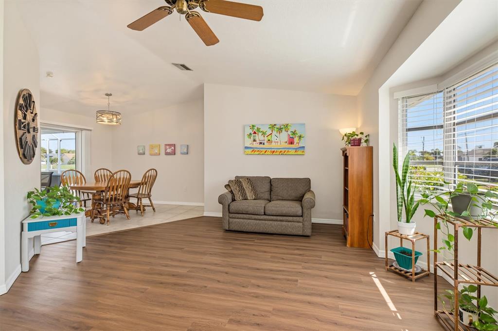A living and dining area with wood-look flooring, a ceiling fan, and a bay window — 26392 LANCER LANE, PUNTA GORDA, FL