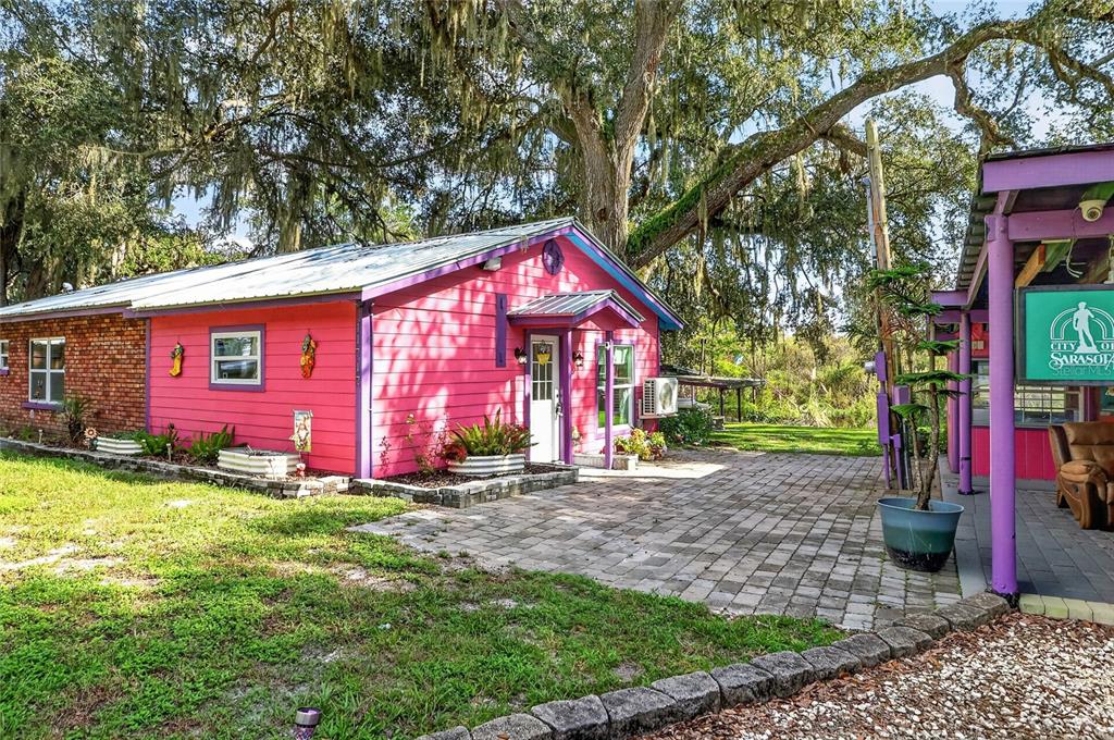 A bright pink house with a metal roof sits on a large, grassy lot — 11717 E SALMON DRIVE, FLORAL CITY, FL