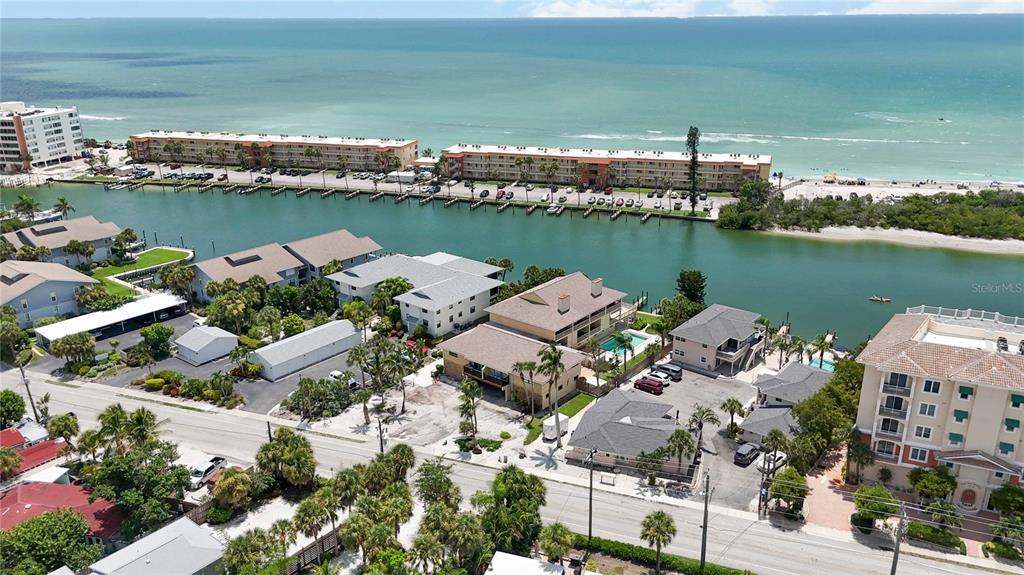 An aerial view shows waterfront condominiums, a canal, and a beach along the coastline — 9034 MIDNIGHT PASS ROAD UNIT 6, SARASOTA, FL