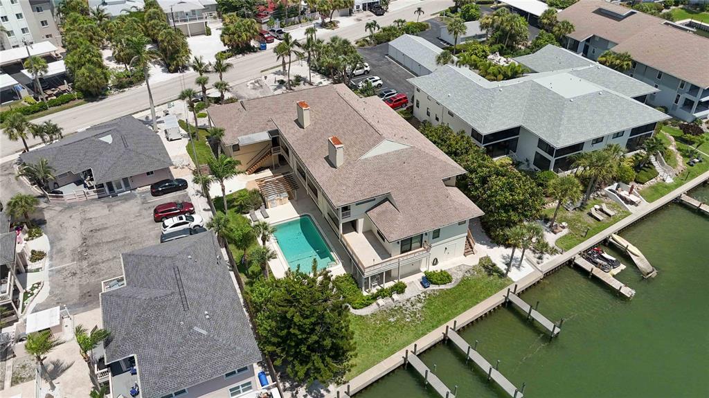 An aerial view shows a multi-story house with a swimming pool and private boat docks — 9034 MIDNIGHT PASS ROAD UNIT 6, SARASOTA, FL