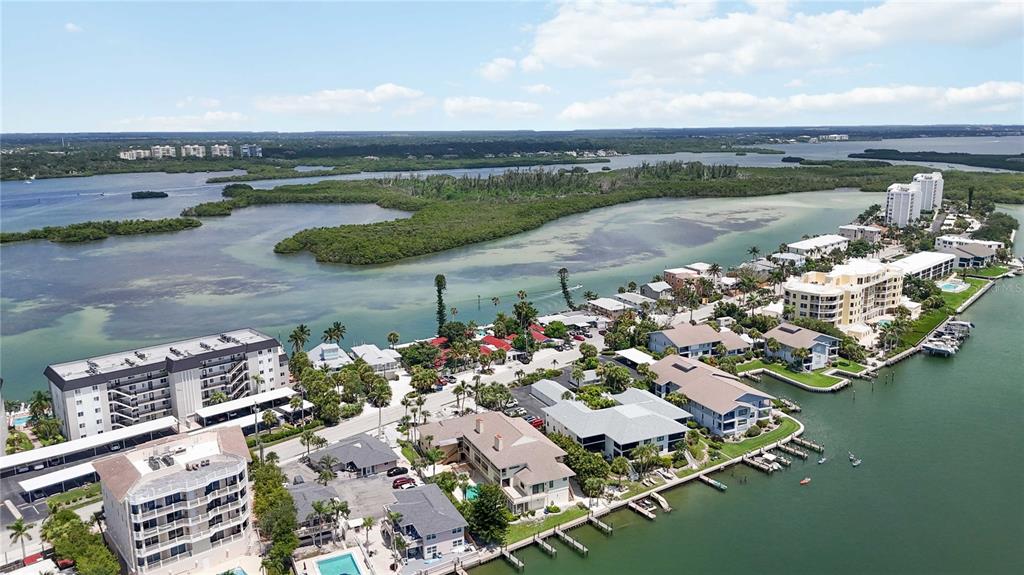 An aerial view shows waterfront condominiums and houses along a coastal inlet with mangroves — 9034 MIDNIGHT PASS ROAD UNIT 6, SARASOTA, FL