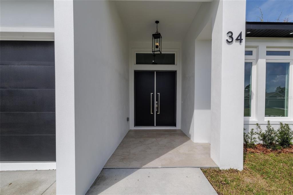 The exterior entrance features a double door, a hanging lantern, and the house number 34 — 34 FALLEN OAK LANE, PALM COAST, FL