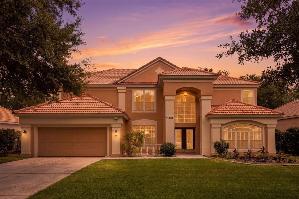 A two-story stucco house with a tile roof, a two-car garage, and a front lawn — 11326 LEDGEMENT LANE, WINDERMERE, FL