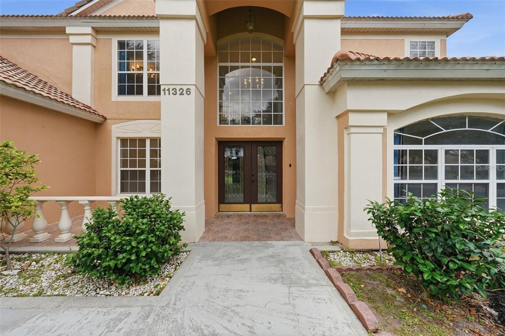 The exterior of a two-story house features a covered entryway with double glass doors — 11326 LEDGEMENT LANE, WINDERMERE, FL
