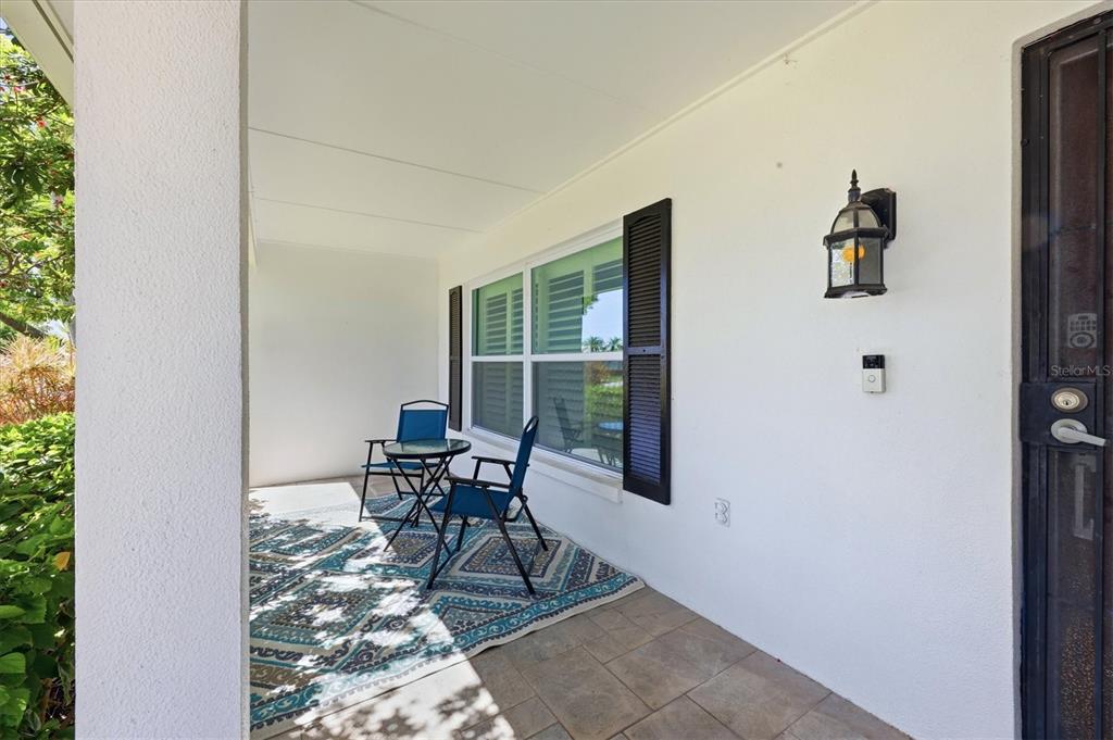 A covered front porch features tiled flooring, a patterned rug, two chairs, and a small table — 9304 41ST STREET N, PINELLAS PARK, FL