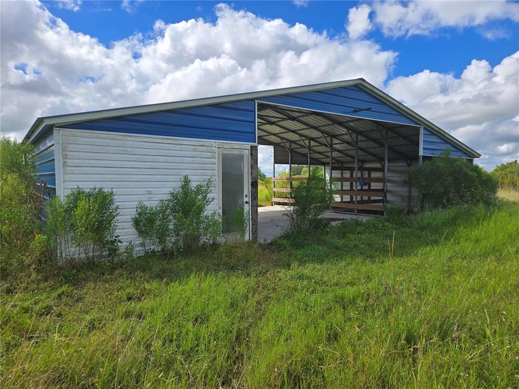 A metal-sided barn with a partially open bay stands in a grassy field — SE PIGGY BACK ROAD, ARCADIA, FL