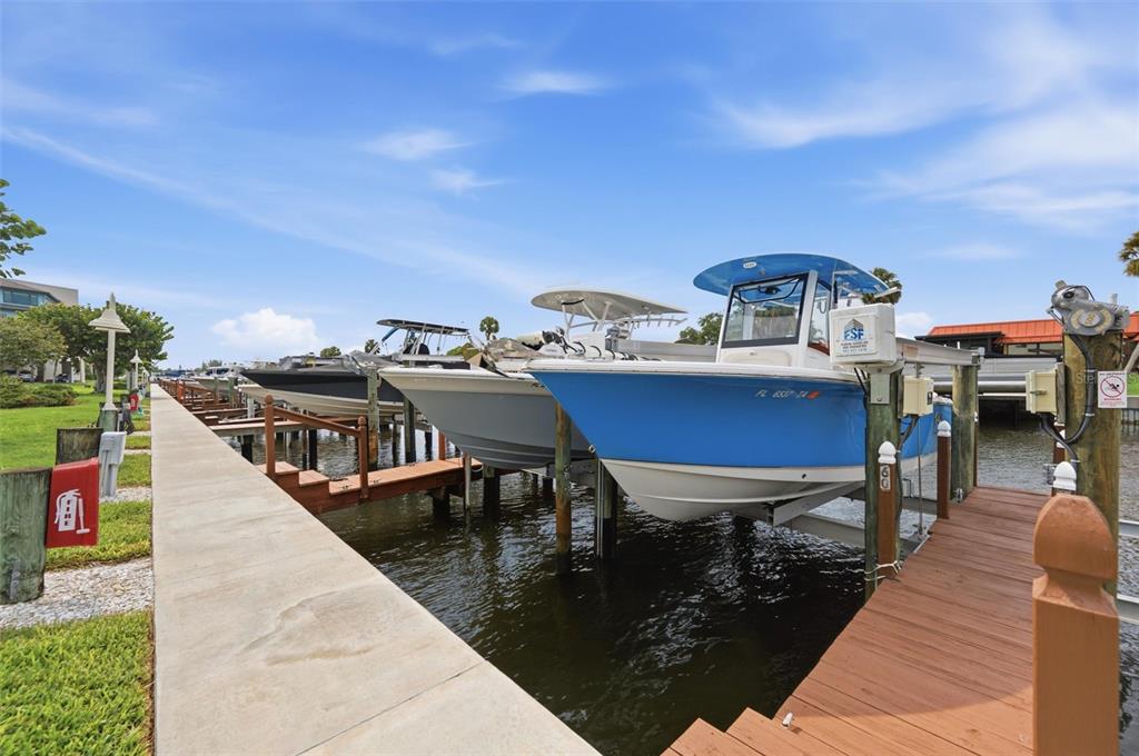 A blue and white motorboat sits on a boat lift at a private dock — 9604 CORTEZ ROAD W UNIT 422, BRADENTON, FL