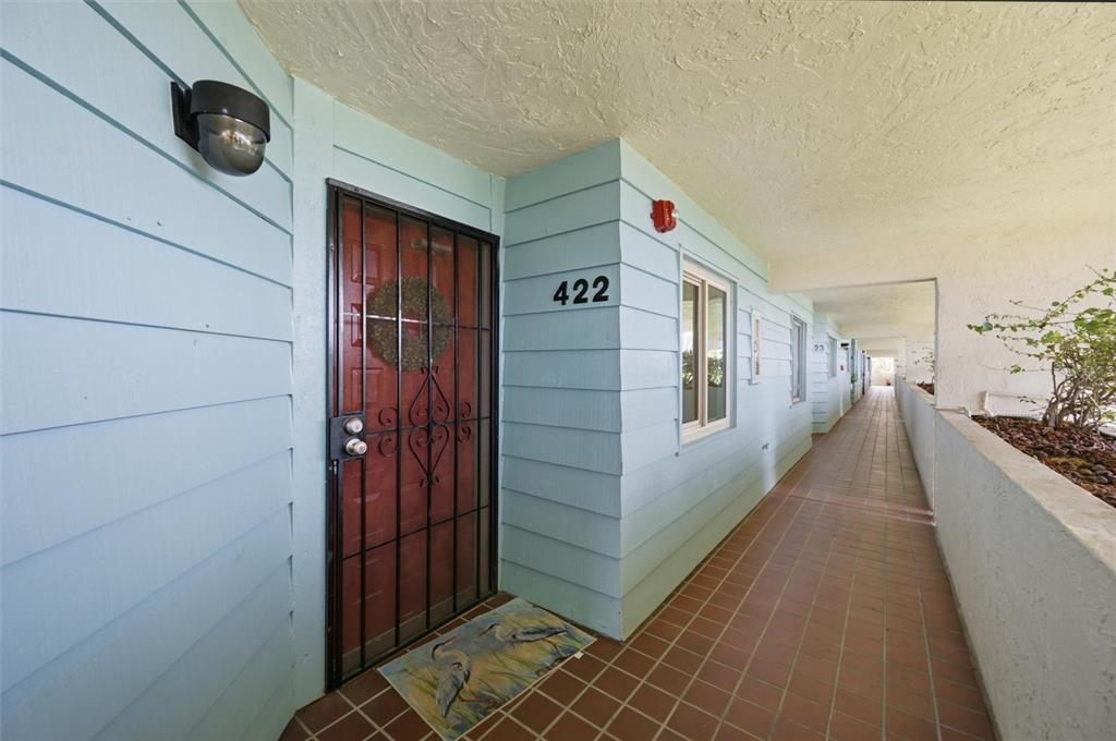 A light blue exterior wall features a red door with a black security gate — 9604 CORTEZ ROAD W UNIT 422, BRADENTON, FL