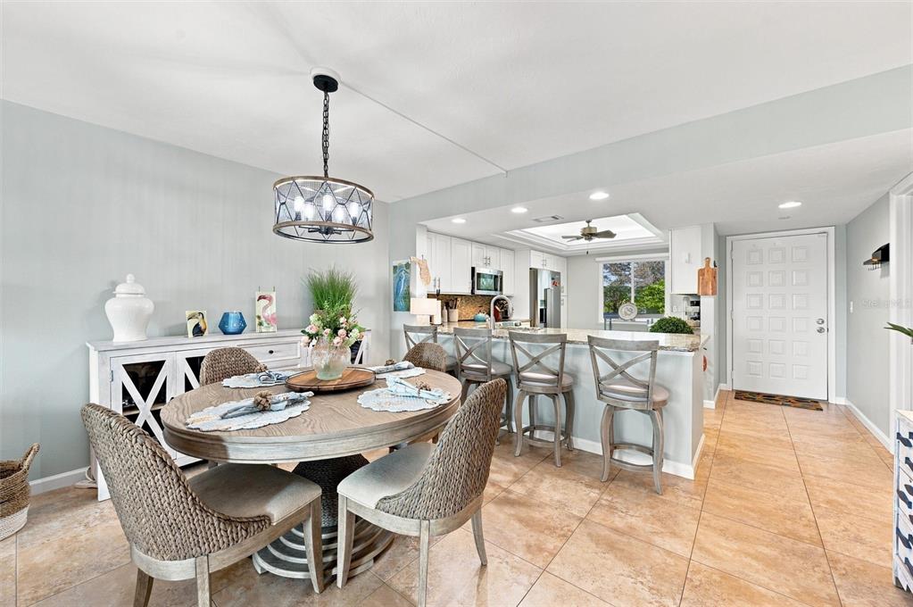A dining area with a round wooden table connects to an open kitchen with bar seating — 9604 CORTEZ ROAD W UNIT 422, BRADENTON, FL