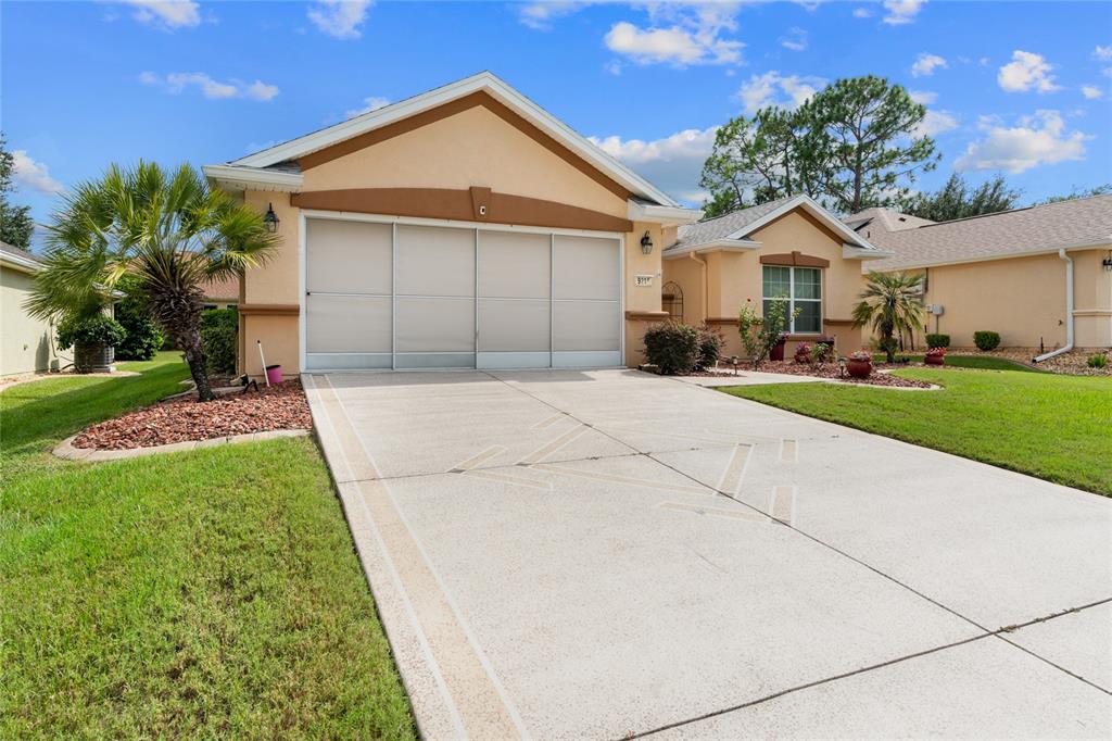 A tan single-story house with a two-car garage and a concrete driveway — 9215 SE 118TH LOOP, SUMMERFIELD, FL