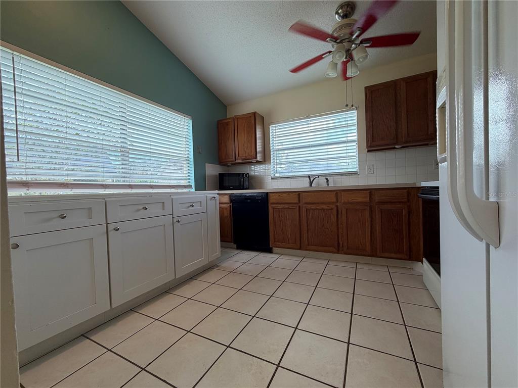 A kitchen features white and wood cabinets, tile flooring, and a red ceiling fan — 13015 BALTIMORE WOODS LANE, ORLANDO, FL