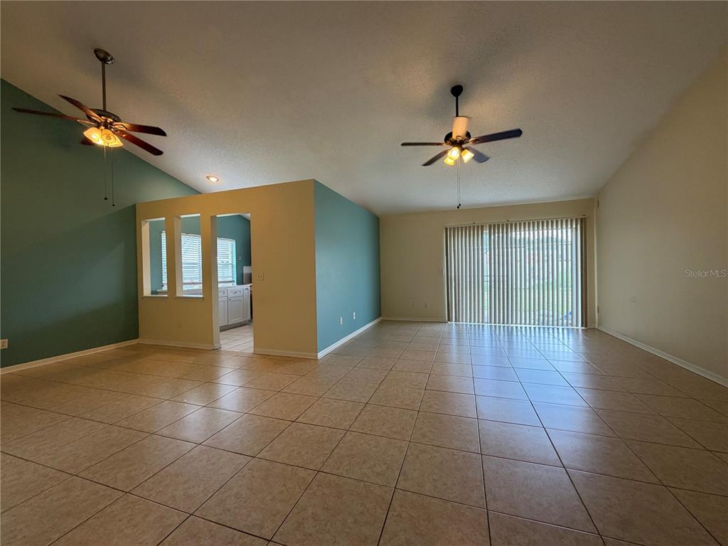 A spacious living area features tile flooring, two ceiling fans, and a partial wall partition — 13015 BALTIMORE WOODS LANE, ORLANDO, FL