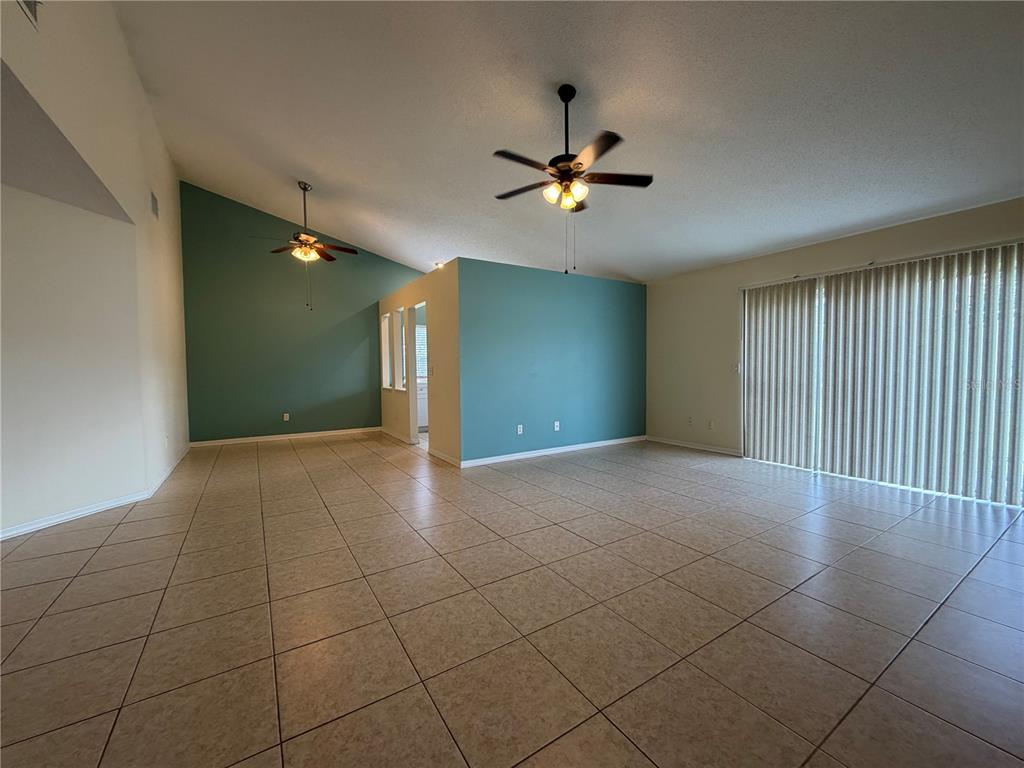A spacious living room features light tile flooring, vaulted ceilings, and teal accent walls — 13015 BALTIMORE WOODS LANE, ORLANDO, FL