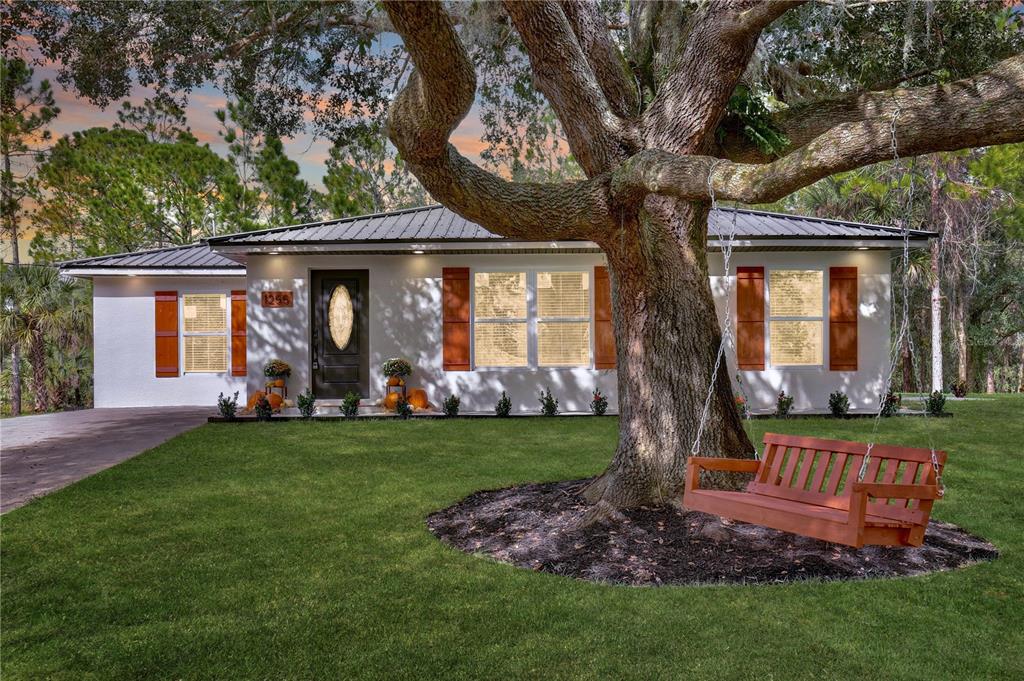 A single-story house with a metal roof, white stucco walls, and a wooden porch swing — 1255 FLINT TRAIL, GENEVA, FL