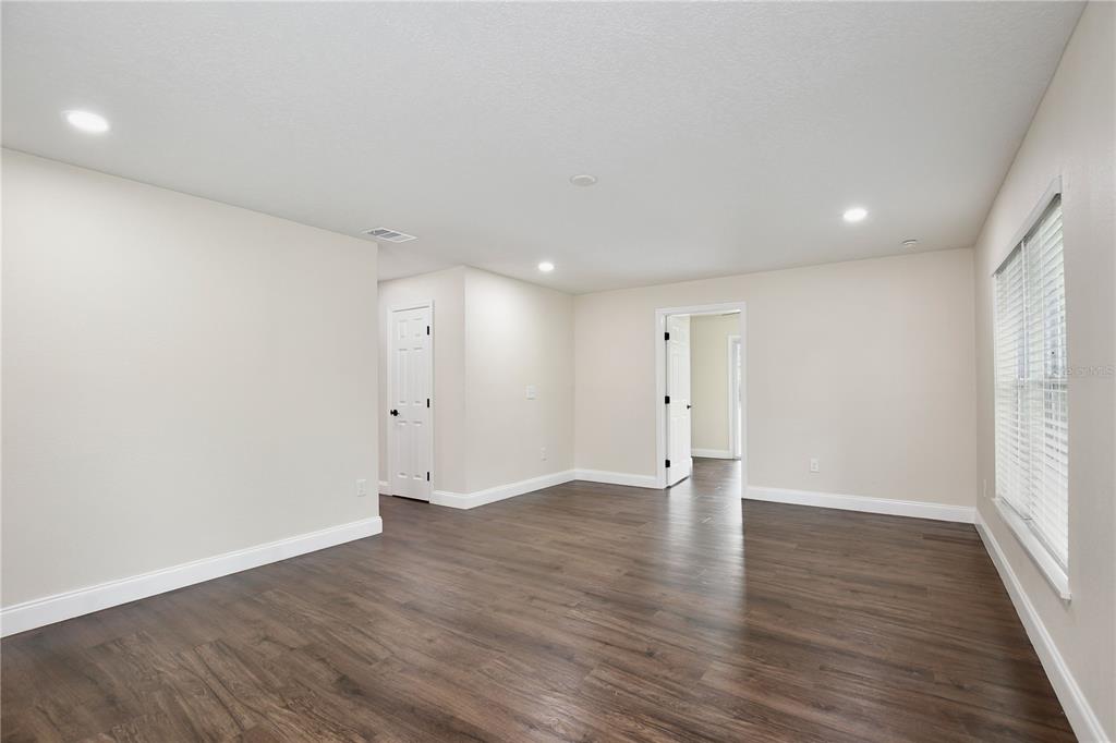 An empty room with dark wood-look flooring, light walls, recessed lighting, and two doorways — 1255 FLINT TRAIL, GENEVA, FL