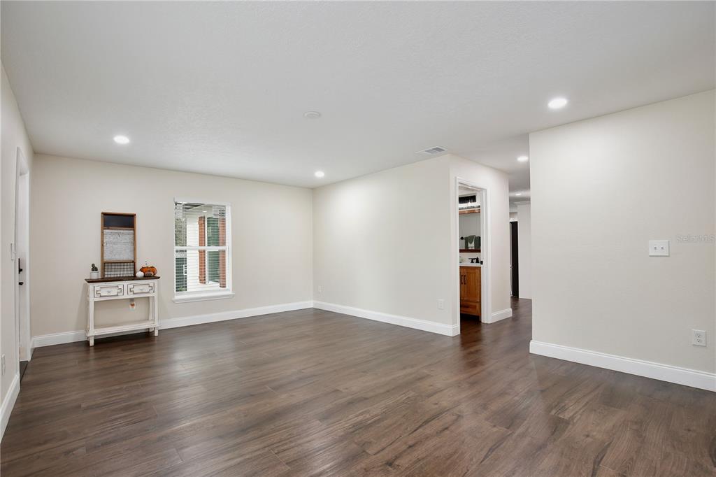 A spacious room with dark wood-look flooring, white walls, recessed lighting, and a small console table — 1255 FLINT TRAIL, GENEVA, FL