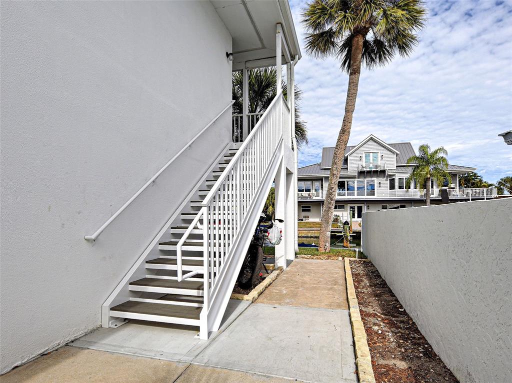 An exterior staircase with white railings leads to an elevated deck beside a house — 902 GIBBS ROAD UNIT 285, VENICE, FL