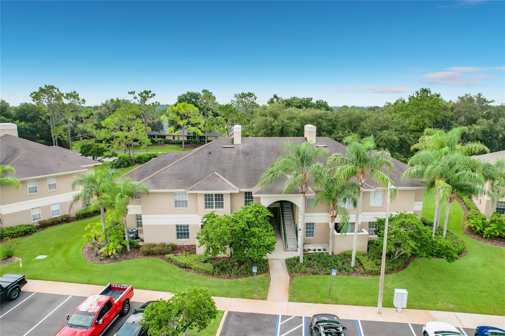 An aerial view shows a two-story apartment building with a tan exterior and palm trees — 1105 EAGLE POND DRIVE UNIT 1105, WINTER HAVEN, FL